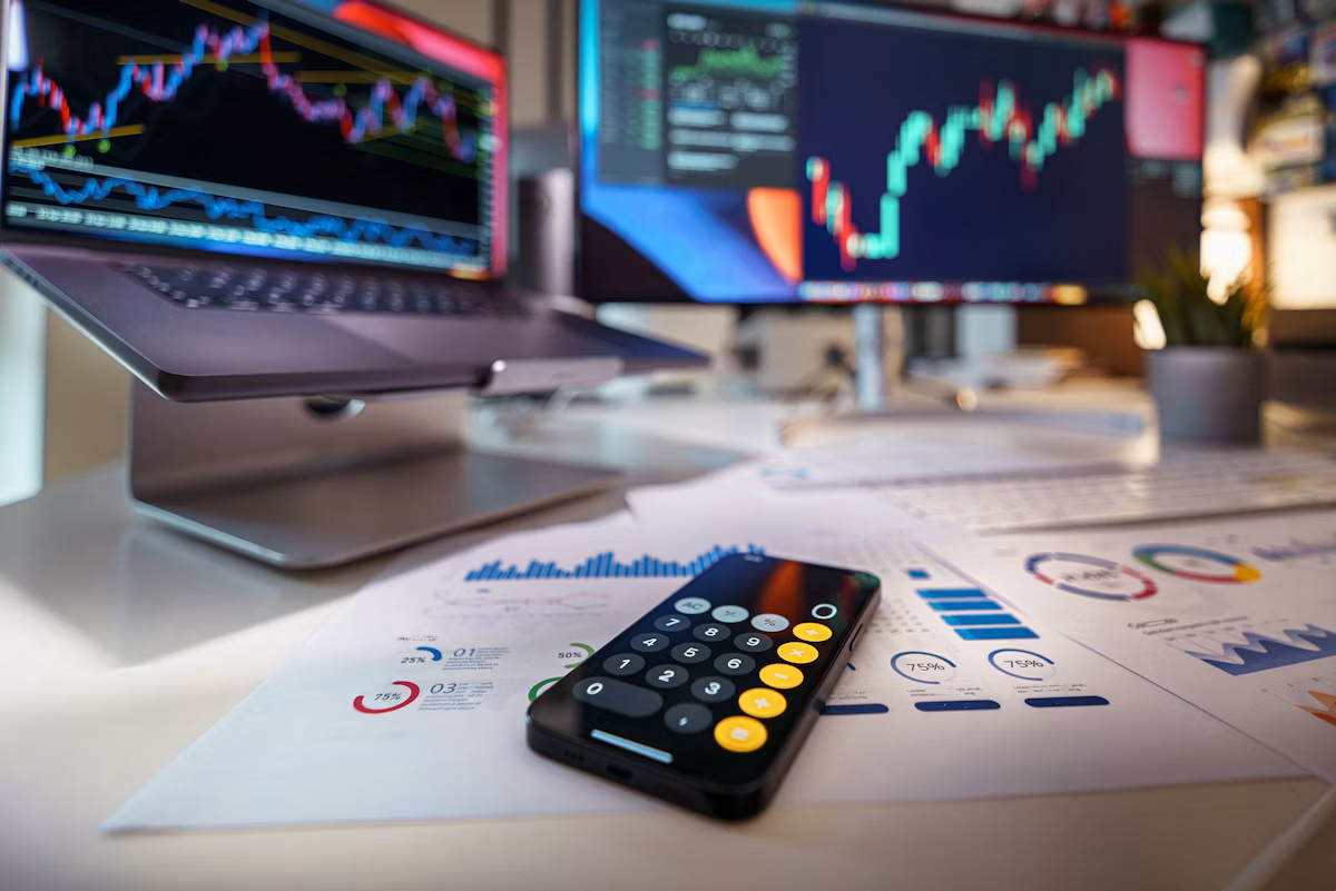 Calculator on a desk with financial charts in the background