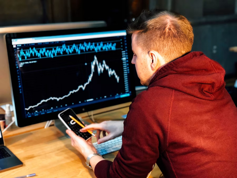 Analyst reviewing a monitor while holding a smartphone